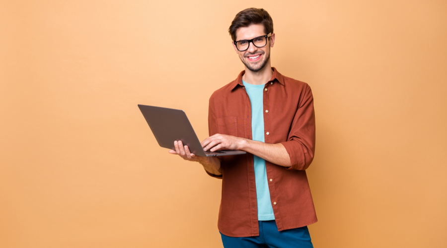 Man smiling using laptop on bright background